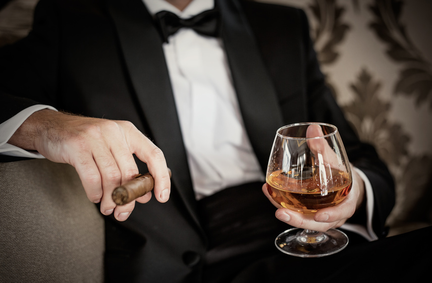 Gentleman hält Glas mit Cognac und eine Zigarre