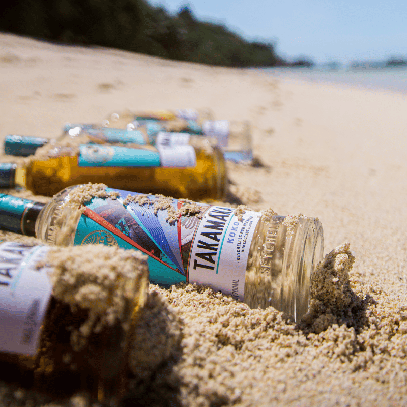 Takamaka Moodbild - Takamaka Flaschen liegen am Strand im Sand