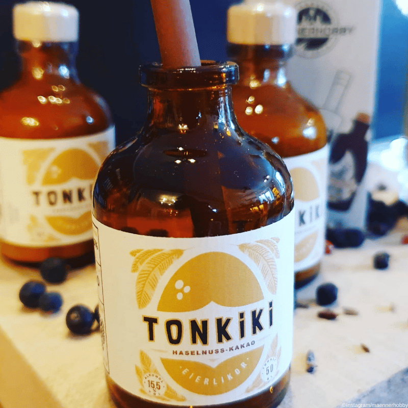 Tonkiki Eierlikoer Moodbild - Flaschen stehen nebeneinander, eine ist offen Blaubeeren liegen um sie drumherum