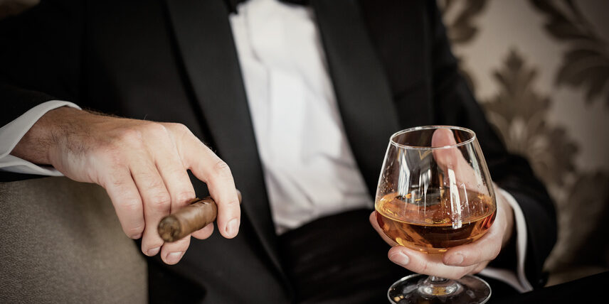 Gentleman hält Glas mit Cognac und eine Zigarre